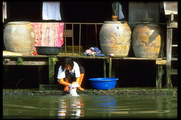Женщина полощит бельё в реке