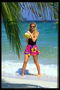 Женщина на берегу океана держит в руках тропический фрукт