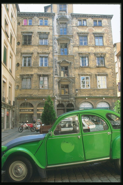 Машина зеленого цвета у стен дома