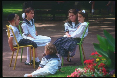Дети сидят на стульях в парке и разговаривают