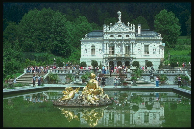 Дворец с белого материала. Статуя цвета золота в фонтане