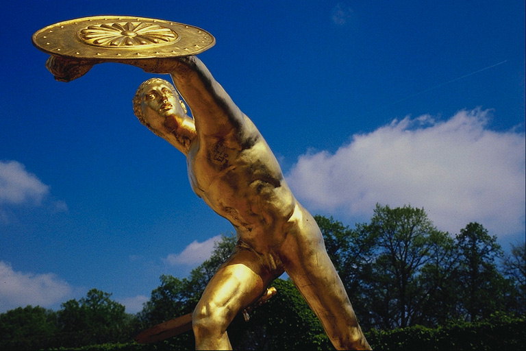 Статуя юноши с щитом в руках. Выполнена с метала золотистого цвета