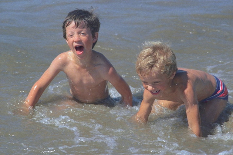 Мальчишки играют в воде на берегу