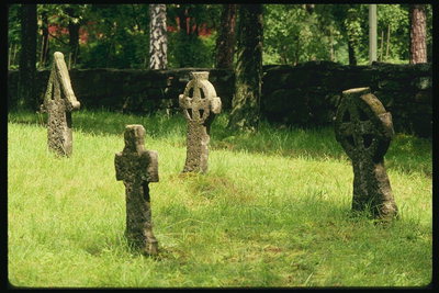 Каменные кресты среди зеленой травы