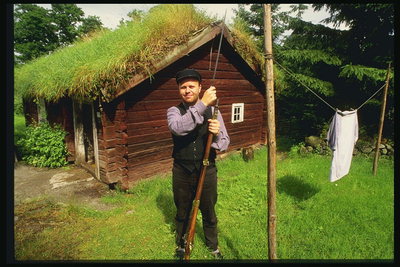 Мужчина у домика с крышей покрытой травой