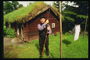 Мужчина у домика с крышей покрытой травой