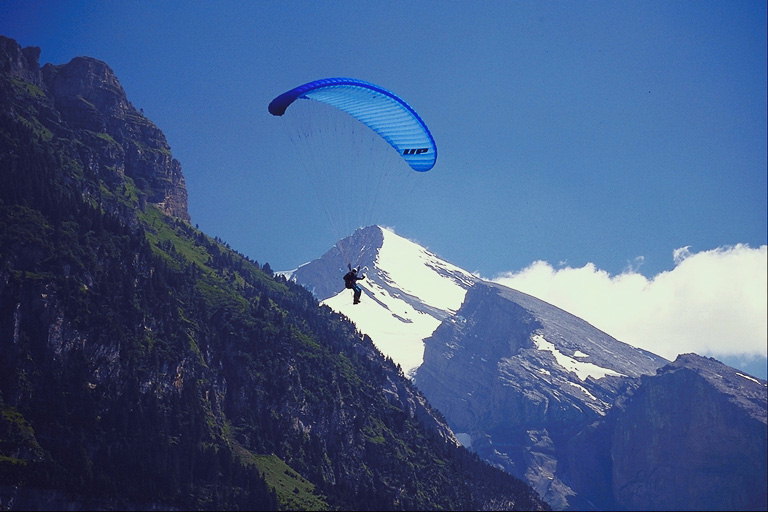 Парашютист летящий с горы. Вершины гор в снегу