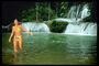 Девушка в ярком салатовом купальнике в водах водопада
