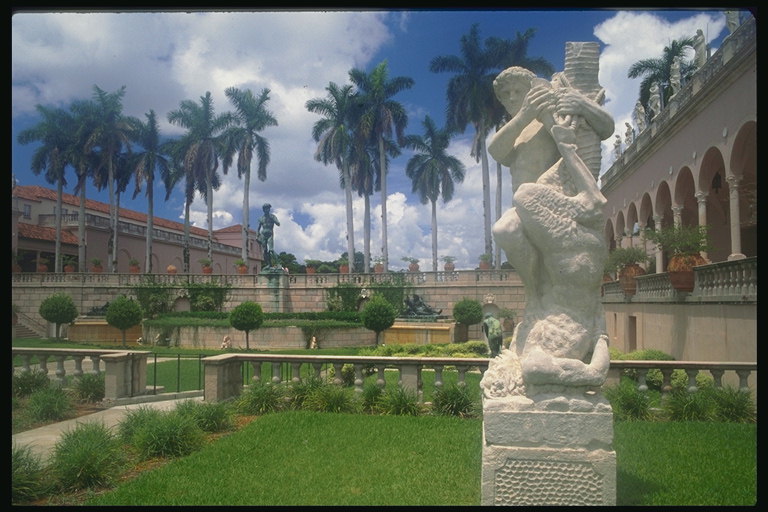 Статуя с белого материала  в парке среди пальм