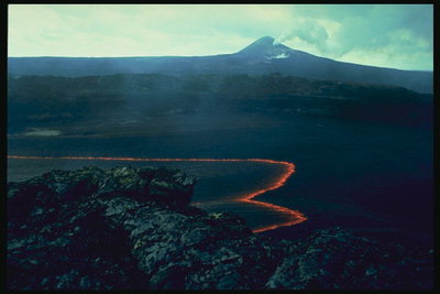 Distant volcano erupt. Diffluent lava at the foot of Mount
