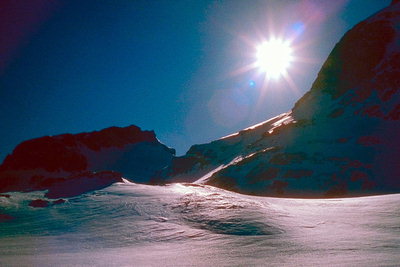 Сверкающий диск солнца за горой