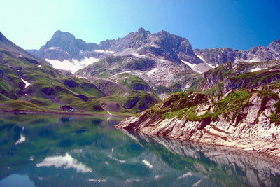Отражение снежных вершин, зеленых склонов гор в озере