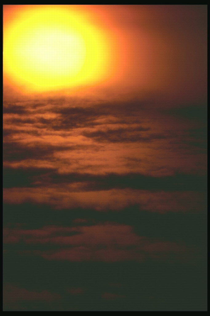 Золотой диск солнца на дымчатых облаках 