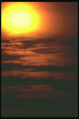 Золотой диск солнца на дымчатых облаках 