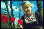 Woman in national dress with red tulips on a background of bare trees