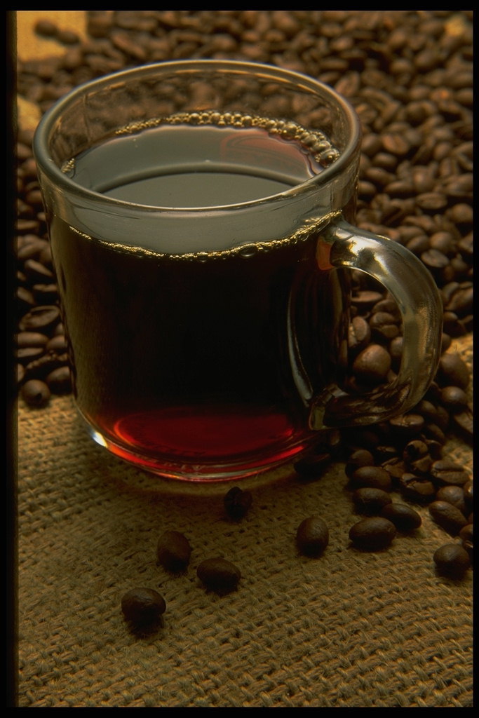 Mustaa kahvia kahvipavut taustalla