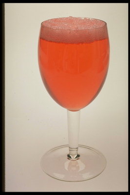 Bebida cor rosa escuro con unha bola de escuma pequeno