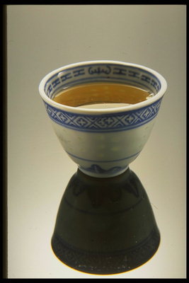 Keramiktasse mit einem blauen Muster und grünem Tee