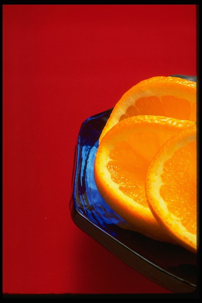 Кружки апельсина на тарелке с синего стекла