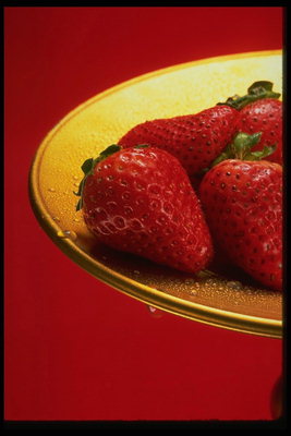 Большие плоды клубники на тарелке золотистого цвета