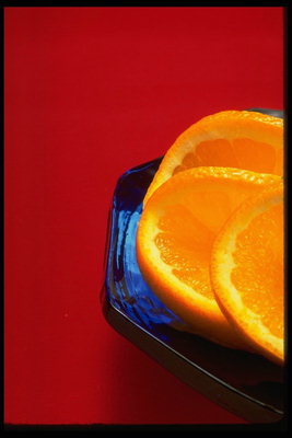 Кружки апельсина на тарелке с синего стекла