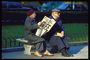 Пожилые люди читают на лавочке газету