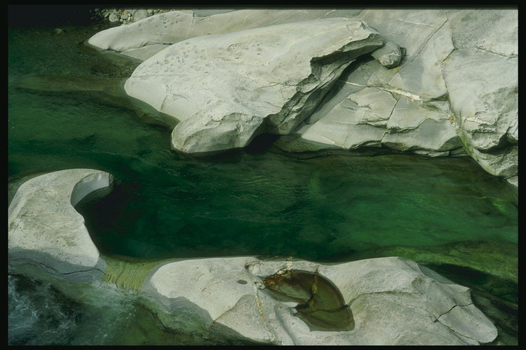 Вода зеленого оттенка среди серых камней