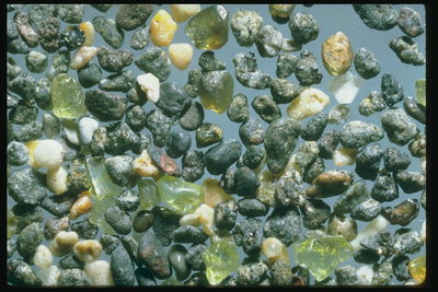 Прозрачные кристалы светло-зеленого цвета среди серых камней