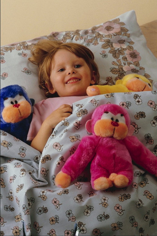 Chica en la cama con los juguetes