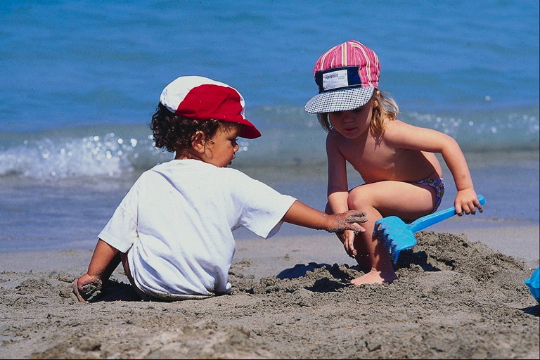Tyttö ja poika leikkivät rannalla