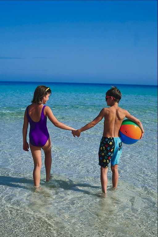 Dievča a chlapec sa lopta chôdzi na pláži