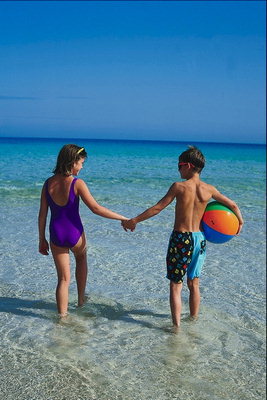 เด็กผู้หญิงและเด็กกับลูกบอลที่เดินบนชายหาด
