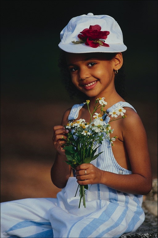 Den lille jenta i en lue og blomster