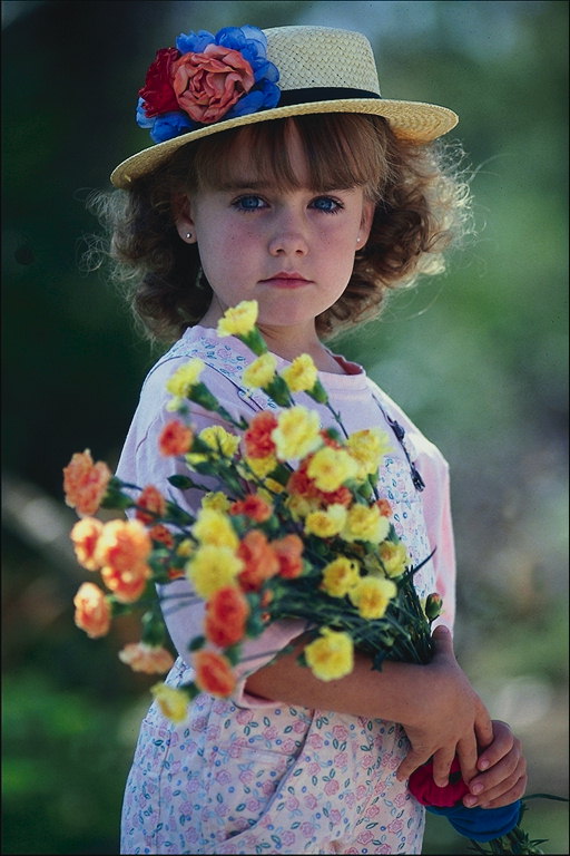 En jente i en hatt med blomster i hendene