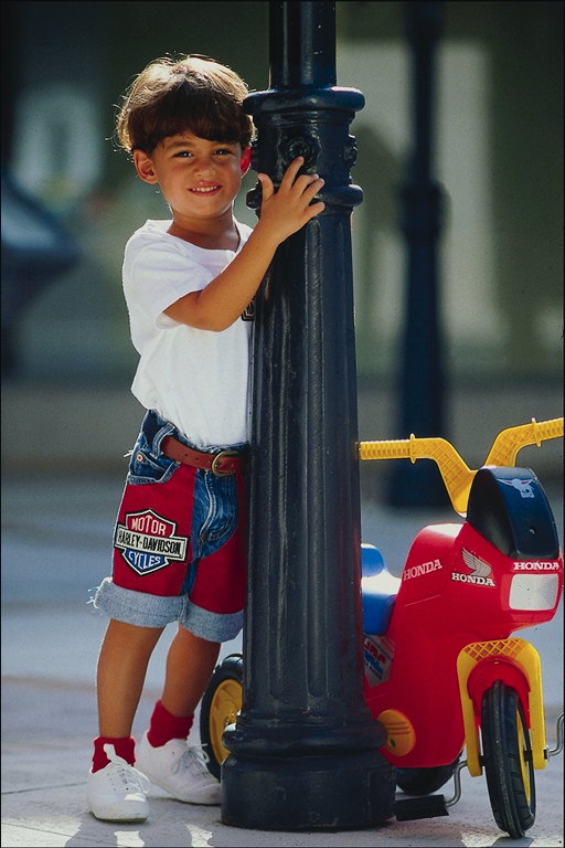 En liten pojke med en cykel i närheten av pelaren