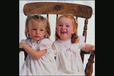 To jenter sitter på en stol