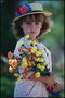 Ένα κορίτσι σε ένα καπέλο με λουλούδια στα χέρια τους