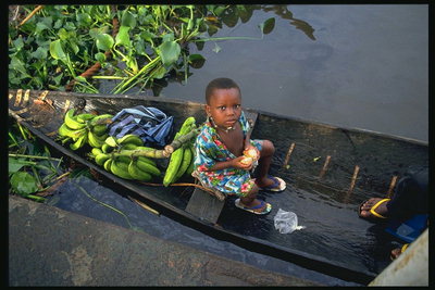 A girl in a boat with a cluster of bananas