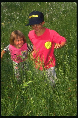 Děti chodí po zelené trávě