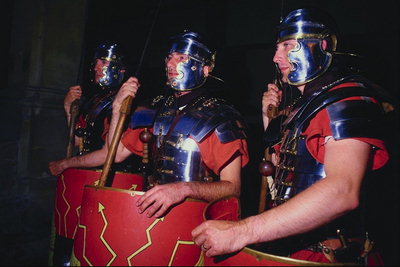 Gutter i kostymer av romerske soldater med skjold