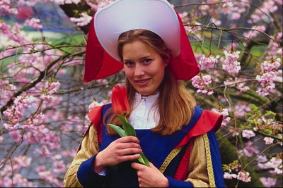 Dievča v kostýmu v klobúku s červenou tulipánov v rukách