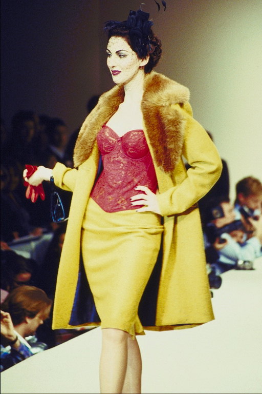 Mustard-colored coat and skirt in tone. Red corset
