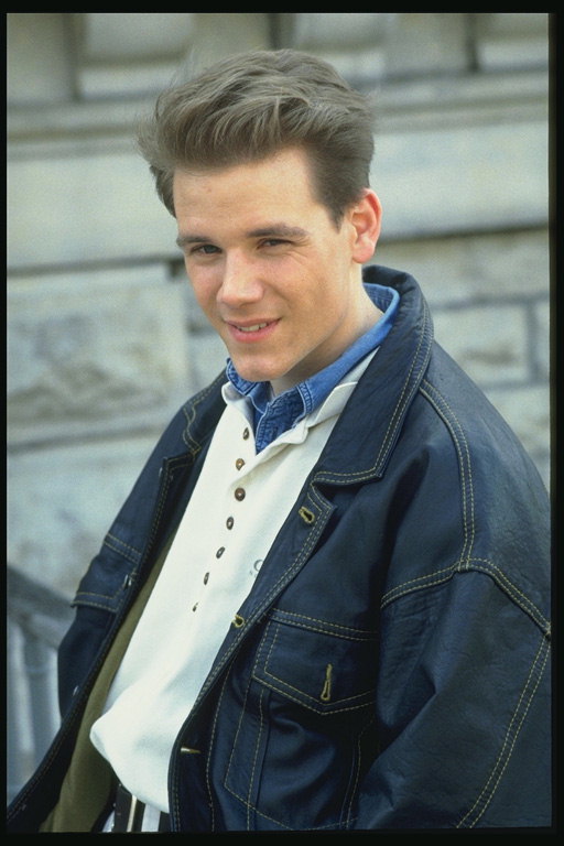 A young man in a white shirt, denim jacket