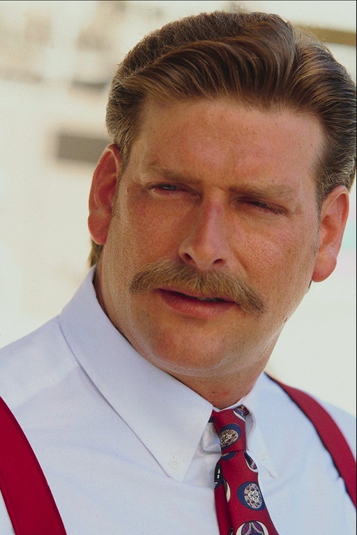 En mand med en mustache i en hvid skjorte