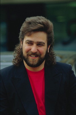 A smiling young man with a beard and long hair