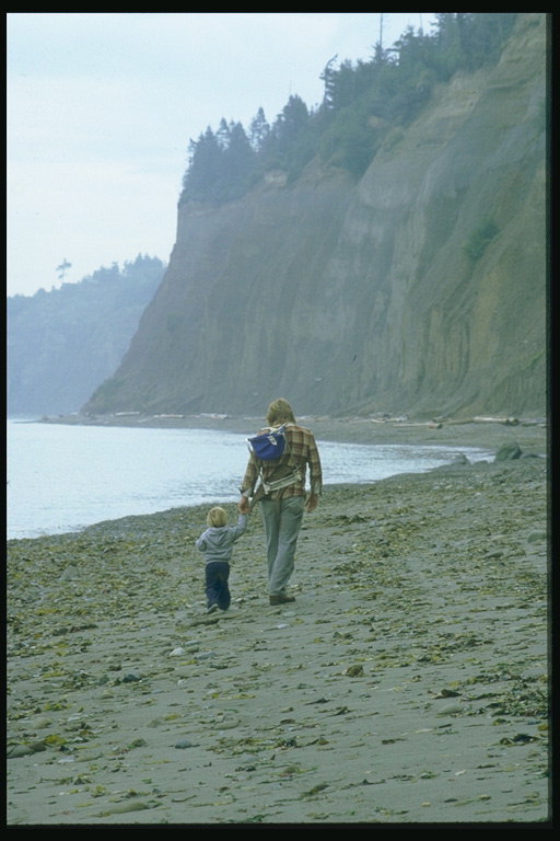 Мужчина гуляет с ребенком вдоль набережной
