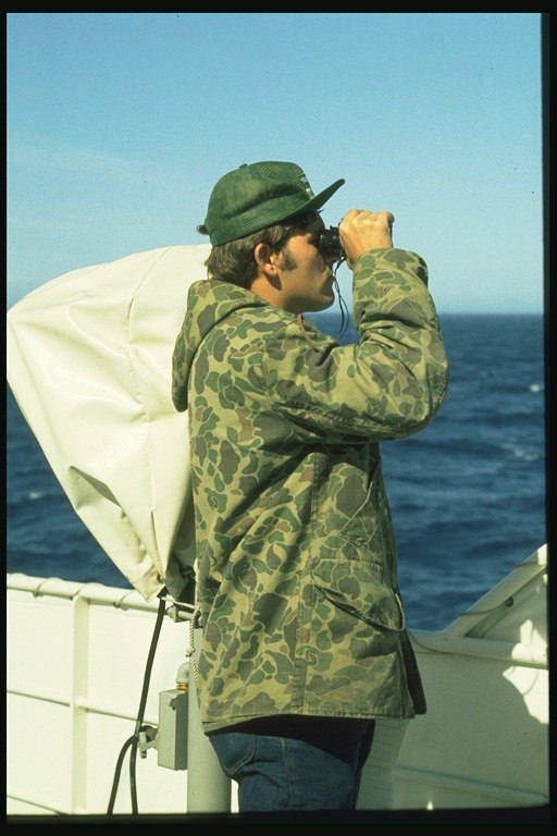 Un bărbat se uită prin binoclu de pe nava