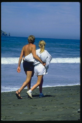 Un tip cu o fata se plimba pe plajă
