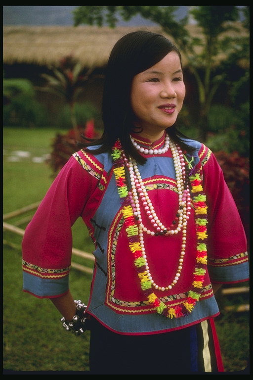 O femeie în rochie naţionale cu margele cu perle şi flori