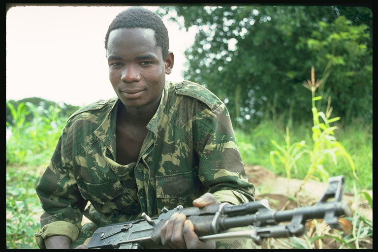 Den unge mand i militæret fatigues med maskinlæsbare pistol i hænderne på